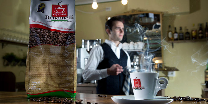 Bendinelli Kaffeeverpackung im Vordergrund, im Hintergrund stehender Mann